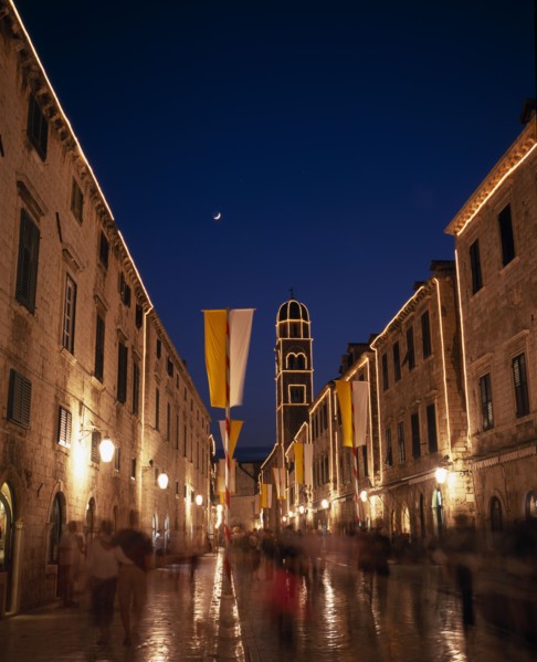 CROATIA, Dalmatia, Dubrovnik, View along the Stradun toward the Franciscan Monastery illuminated at
