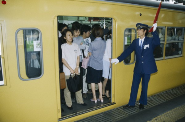 JAPAN, Honshu, Tokyo, Commuters in packed train with guard about to close doors.