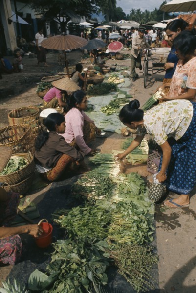 LAOS, Markets, Female vendors and customers at roadside stalls selling herbs and vegetables.
