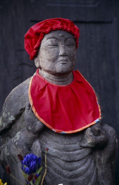JAPAN, Honshu, Kamakura, Jizo statue traditionally dressed in red bibs by bereaved mothers and