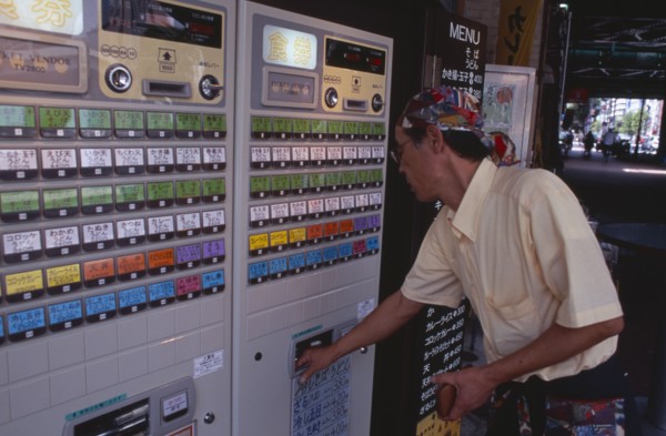 JAPAN, Honshu, Tokyo, Shimbashi. Man using Restaurant Ticket vending machine