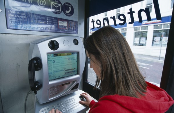 COMMUNICATIONS, Phone Box, Young woman using a public BT Internet phone booth.