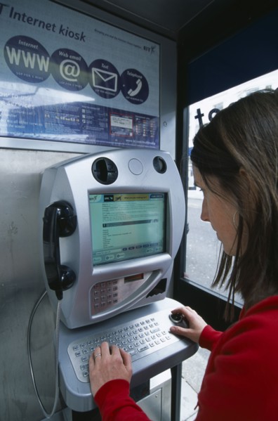 COMMUNICATIONS, Phone Box, Young woman using a public BT Internet phone booth.