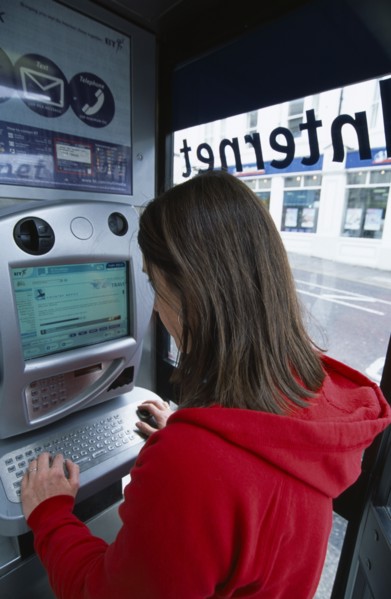 COMMUNICATIONS, Phone Box, Young woman using a public BT Internet phone booth.