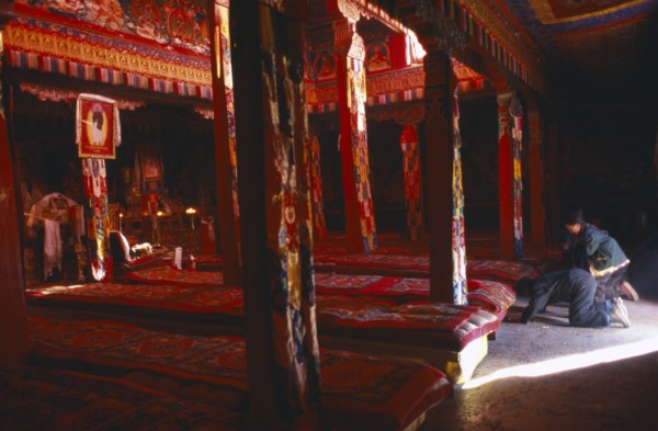TIBET, Sakya, View through the interior of a temple in red ambient light towards the monks long