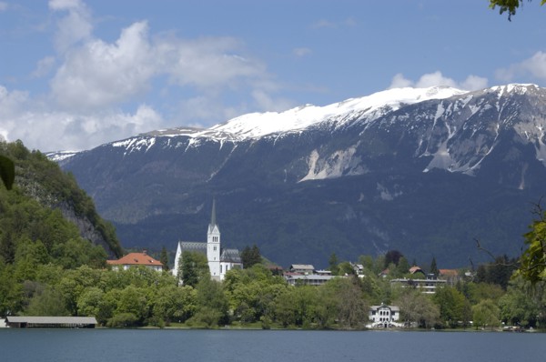 SLOVENIA, Lake Bled, Pristiva. View from the lake toward the Church of St Martin with snow capped