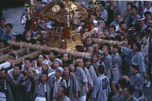 JAPAN, Honshu, Tokyo, Shinjuku. Crowd of people carrying Mikoshi throught the street during a