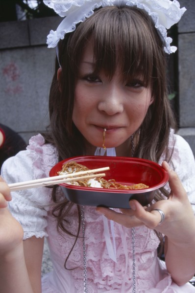 JAPAN, Honshu, Tokyo, Harajuku District. Portrait of young teenage girl eating noodles