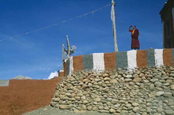 NEPAL, Mustang, Monk standing on painted terrace of Tsarang’s temple.