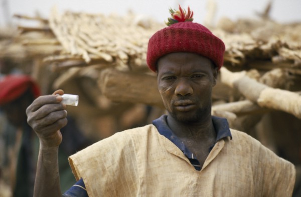 BURKINA FASO, Sahel, Miner holding up phial of gold dust.