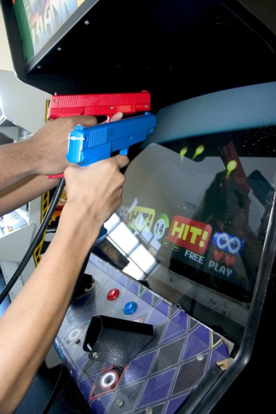 USA, Minnesota, St Paul, Teenagers shooting Point Blank video game with red and blue replica 45