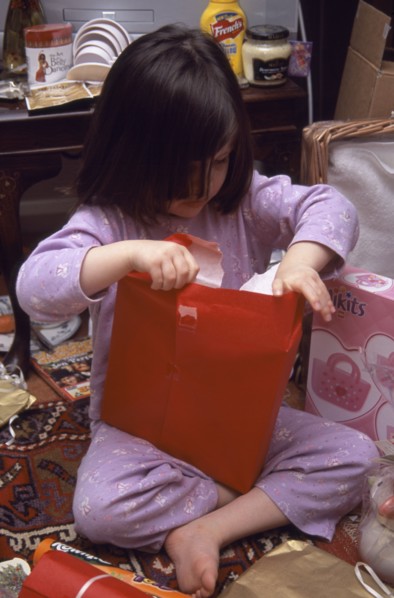 FESTIVALS, Christmas, Presents, Five year old girl sitting on the floor opening her Christmas