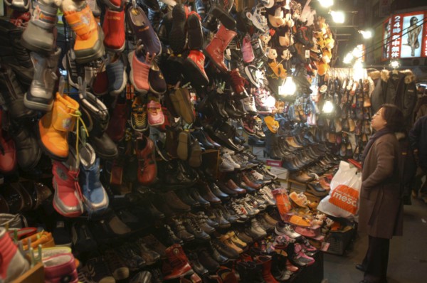 KOREA, Seoul, Namdaemun Market. Woman shopping for shoes on a cold December night