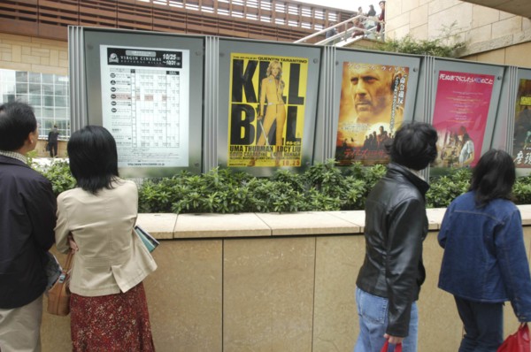 JAPAN, Tokyo, Roppongi, Roppongi Ark Hills Ark Tower. Japanese looking at poster for foreign film