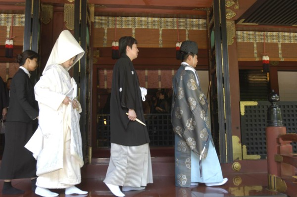 JAPAN, Honshu, Tokyo, Nezu. Shinto priest leads newly married couple out of Nezu Jinja shrine after