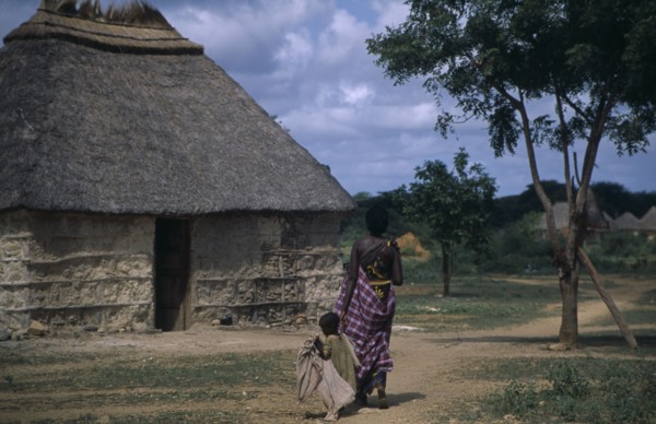 SOMALIA, Tribal People, Woman and child walking towards traditional thatchedhouse near Baidoa.