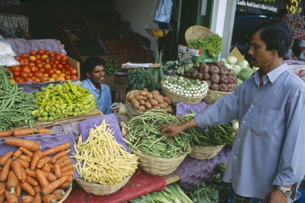 SRI LANKA, Colombo, Pettah District. Customer at a market stall selling vegetables