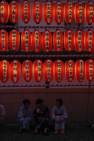 JAPAN, Chiba, Narita, "Teenage girls in yukata, summer kimono, sit beneath chochin lanterns each