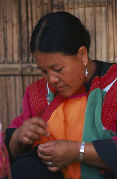 THAILAND, Chiang Mai Province, Lisu woman sewing in front of the house