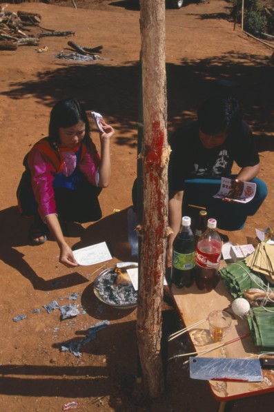 THAILAND, Chiang Mai Province, Bahn Mae Phaem, Lisu girl and man burning imitation money beside New
