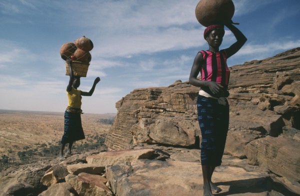 MALI, Bandiagara Cliffs, One woman carrying beer and another pots on their heads standing at the