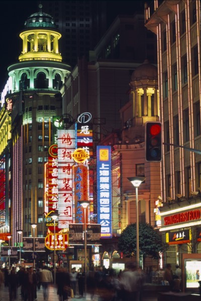 CHINA, Shanghai, Nanjing Road at night with illuminated neon signs and crowds of people in blurred