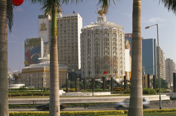 CHINA, Macau, Casino Lisboa.  Exterior framed by palm tree trunks in foreground.
