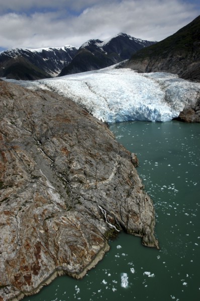 USA, Alaska, Tracy Arm Fjord, View over rocky edged waterway toward icy slope and mountain peaks
