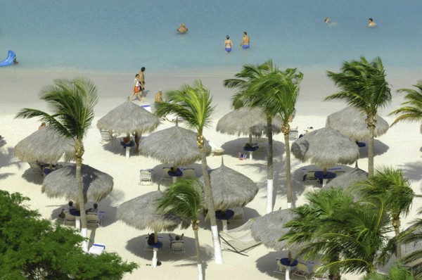 WEST INDIES, Dutch Antilles, Aruba, View looking down on white sandy beach lined with thatched