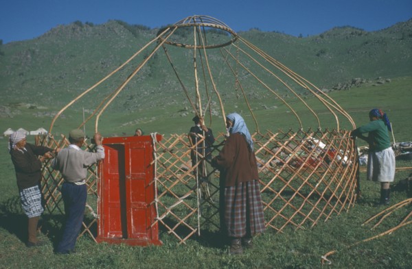 CHINA, Xinjiang, Altai Region, "Kazakh nomads building kigizuy, erecting circular frame and doorway