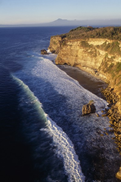 INDONESIA, Bali, Coastline, View north at sunset from Uluwatu Temple along rocky coastline towards