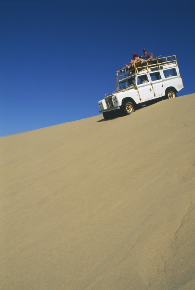NAMIBIA, Skeleton Coast, Terrace Bay, Dune driving on the Roaring Dunes with jeep on crest of dune.
