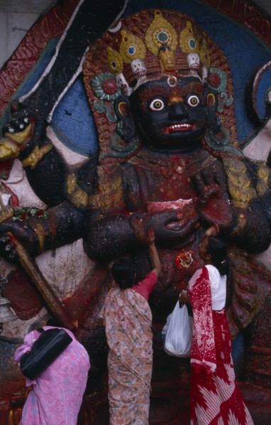 NEPAL,  , Kathmandu, Women making offerings at the Kala Bhairab or black Shiva in Durbar Square