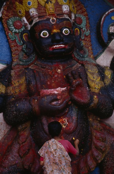 NEPAL,  , Kathmandu, Woman making offerings at the Kala Bhairab or black Shiva in Durbar Square