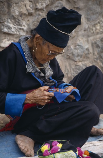 LAOS, Luang Prabang, Hmong woman embroidering traditional textile.
