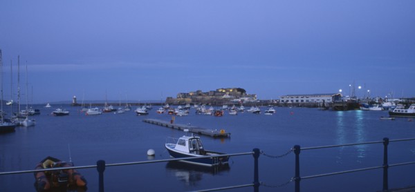 UNITED KINGDOM, Channel Islands, Guernsey, St Peter Port. Cornet Castle at dusk seen from across