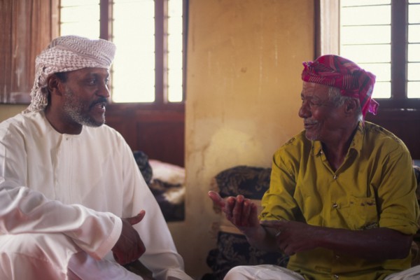 OMAN, Sur, "Discussioin between two Omanis, including traditional fisherman on the right hand side