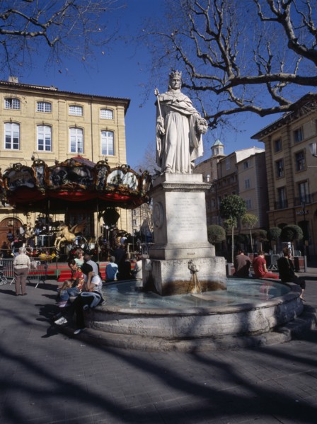 FRANCE, Aix en Provence, "Statue in centre of water fountain, people sat on edge. Carousel and