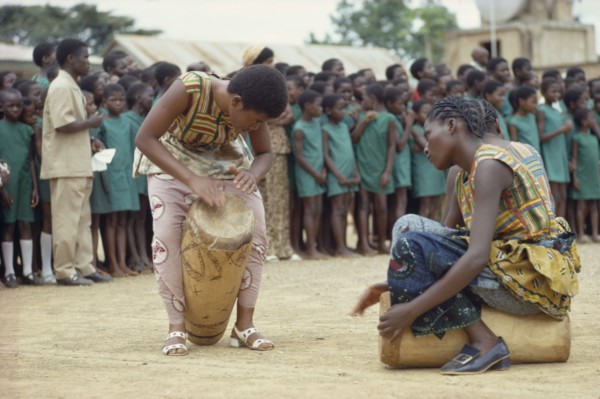 CONGO, Tribal People, African women drummers with group of schoolchildren listening behind.
