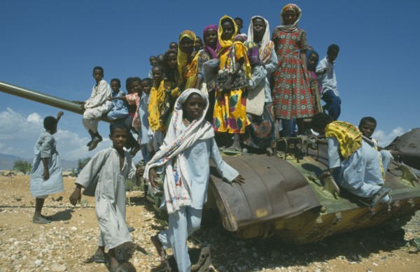 ERITREA, Children, Children playing on rusting tank on road between Asmara and Keren near Aderde.