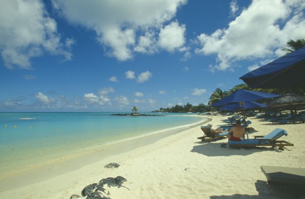 MAURITIUS, Grand Bay, The beach at the Mauritius Hotel. People on sun loungers  and umbrellas.
