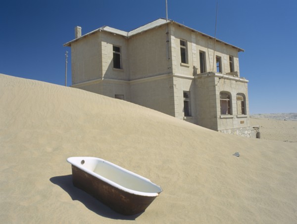 NAMIBIA, Kolmanskop, A house with a bath tub in the foreground  with desert sands encroaching.