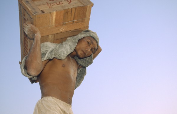MYANMAR, Mandalay Dock, "Man carrying a crate above his head, wearing head scarf. Banks of the