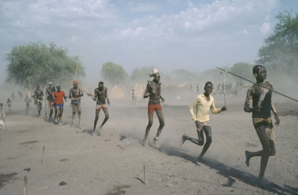 SUDAN, People, Young Dinka men carrying spears and running in line.