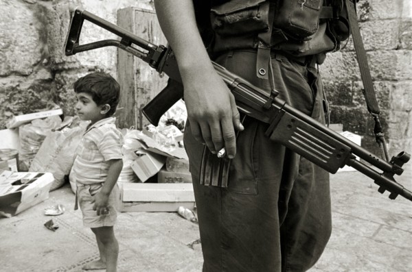ISRAEL, Jerusalem, "Israeli soldier with rifle and cigarette relaxes in the Arab Quarter, small boy