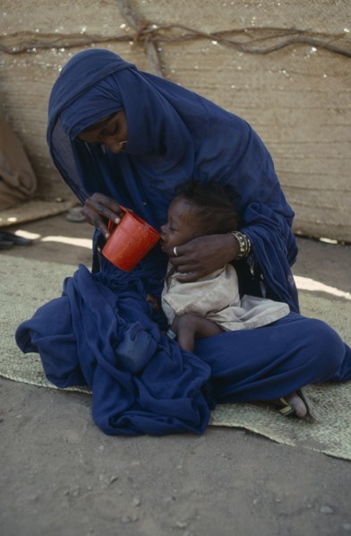 SUDAN, North East, Mother helping her malnourished child to drink at Sinkat feeding centre.