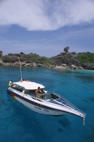 THAILAND, Similan Islands, Ko Bangu, People on board a small motor boat near the rocky shore.