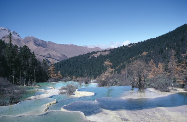 CHINA, Sichuan Province, Huanglong, View across pools formed by calcium carbonate in water towards