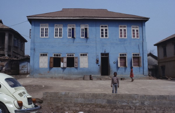 NIGERIA, Inagbiji, Blue painted exterior of typical house with wooden shutters and children in yard
