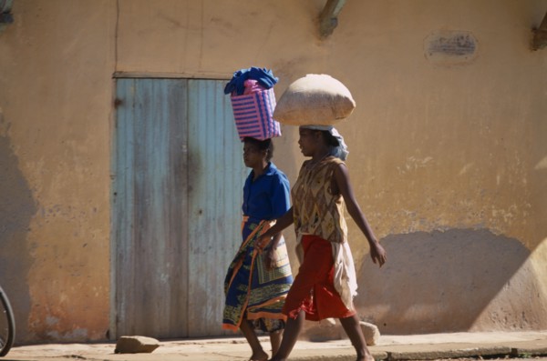 MADAGASCAR, Ambalavao, Two women wearing colourful clothing walking along a street next to a